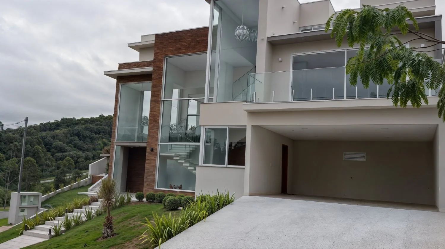 Fachada em pedra e vidro com pé-direito duplo e escada suspensa em residência construída pela Tioda